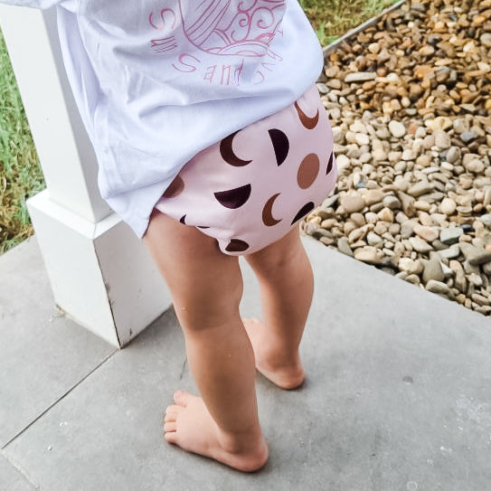 Image shows a child wearing a cloth nappy with pictures of the moon at different phases. 
