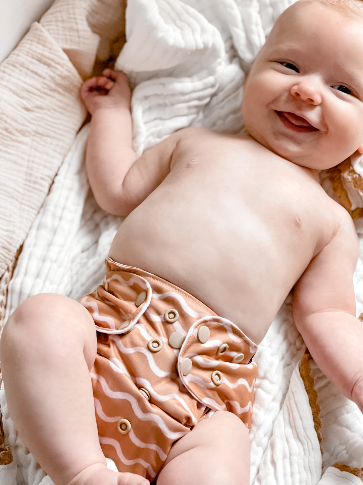 A cute baby wearing an earth waves reusable nappy and smiling